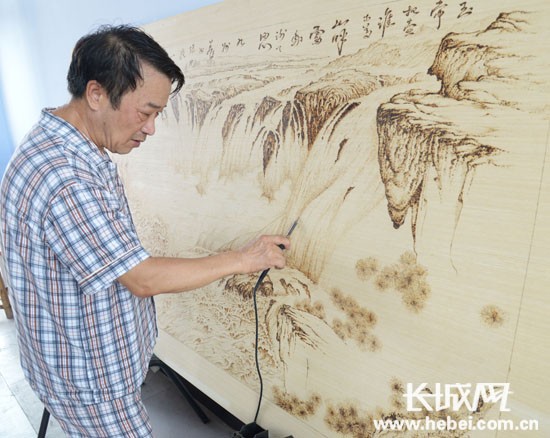 　　姚春生正在創作木板燙畫。古冶區委宣傳部/供圖