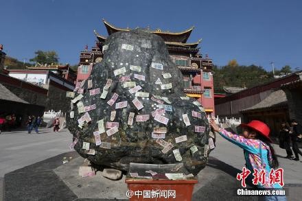 游客在石頭上貼錢