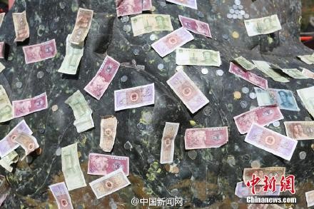 游客在石頭上貼錢