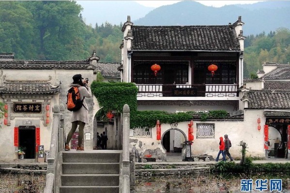 在宏村古村落南湖景區，一名游客在石拱橋上拍攝風景照片
