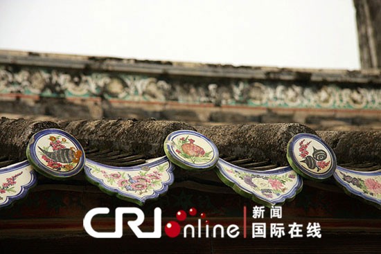 白色為底的圓盤形飾花瓦當上面畫著石榴、馬蹄、茄子等水果和蔬菜